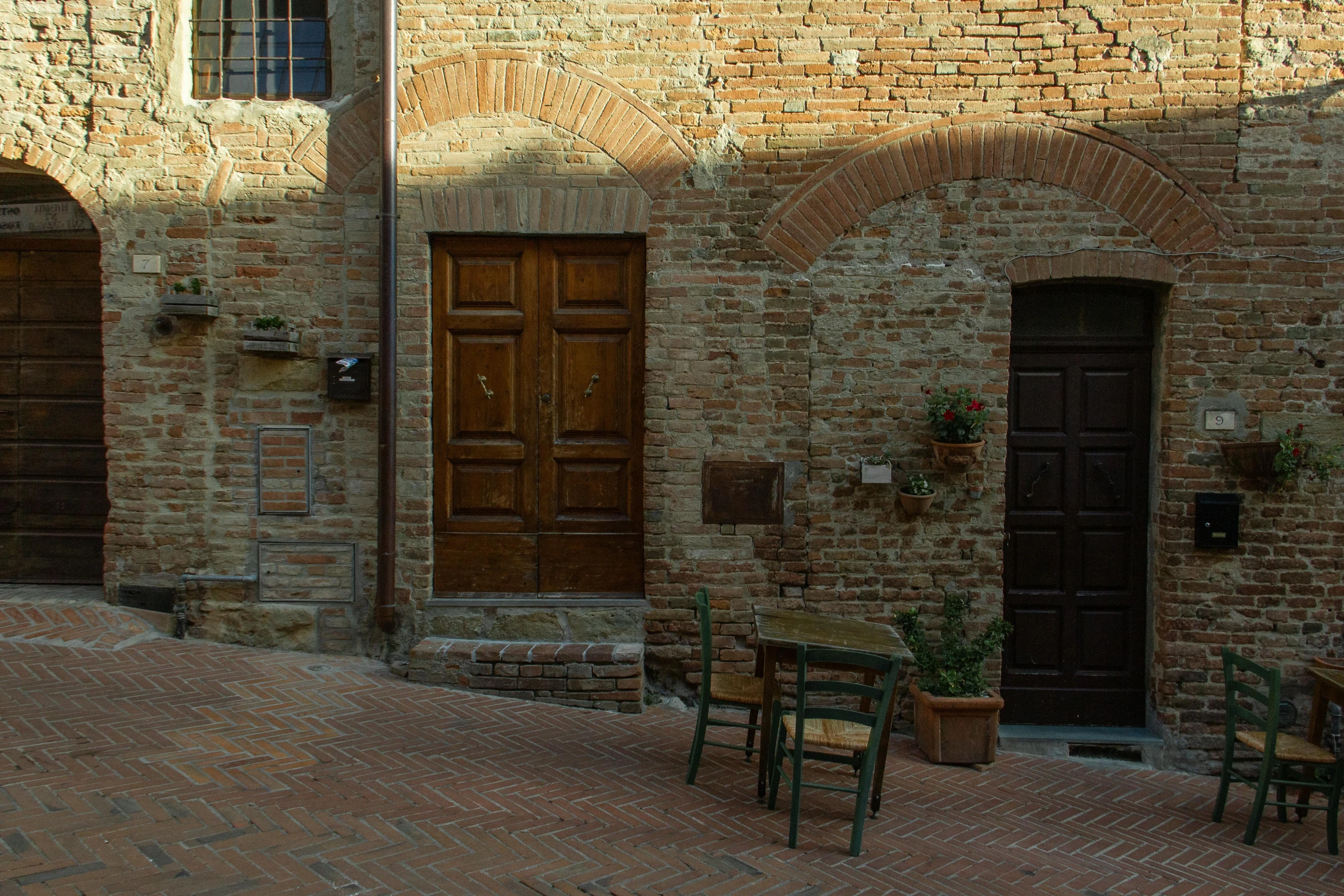 a couple of benches sitting near two brick buildings