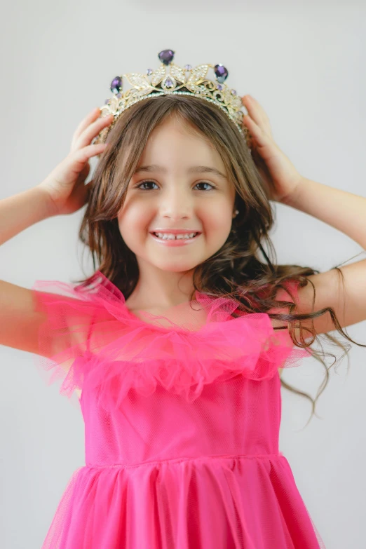 a smiling little girl wearing a tiara over her head