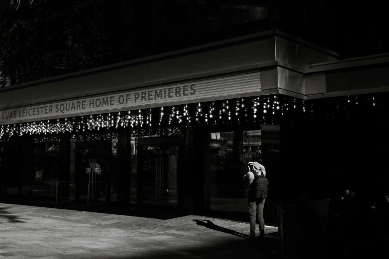 black and white pograph of person waiting for bus at street corner