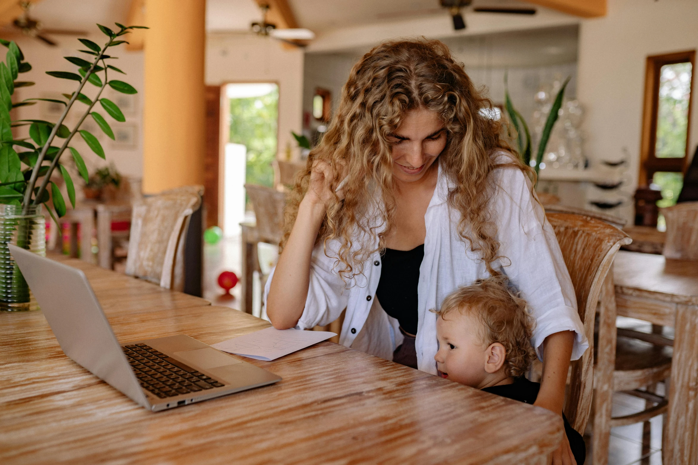 a woman with long hair sitting in front of her laptop