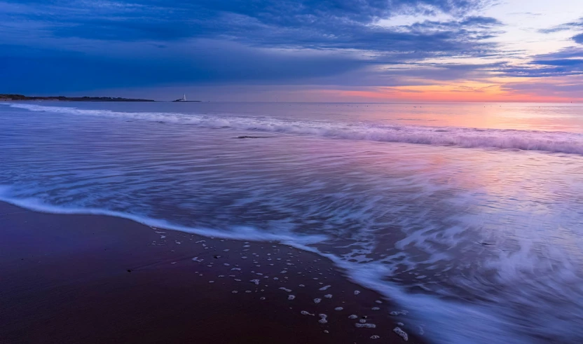 a sunset with waves coming in on the beach