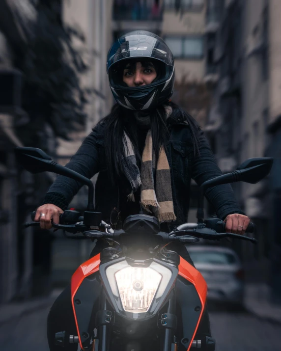 a man in a black jacket and scarf on a motorcycle