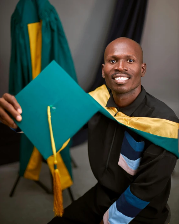 a man is holding up a graduation cap