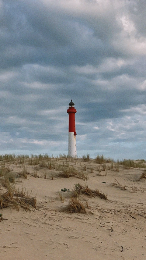 a lighthouse stands in the middle of an empty beach