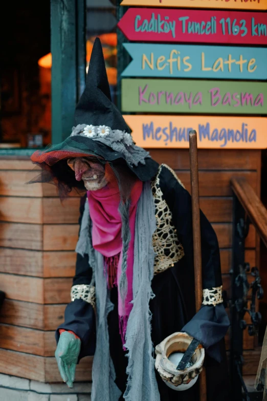 a person dressed up in costume, carrying a broom and wearing a hat