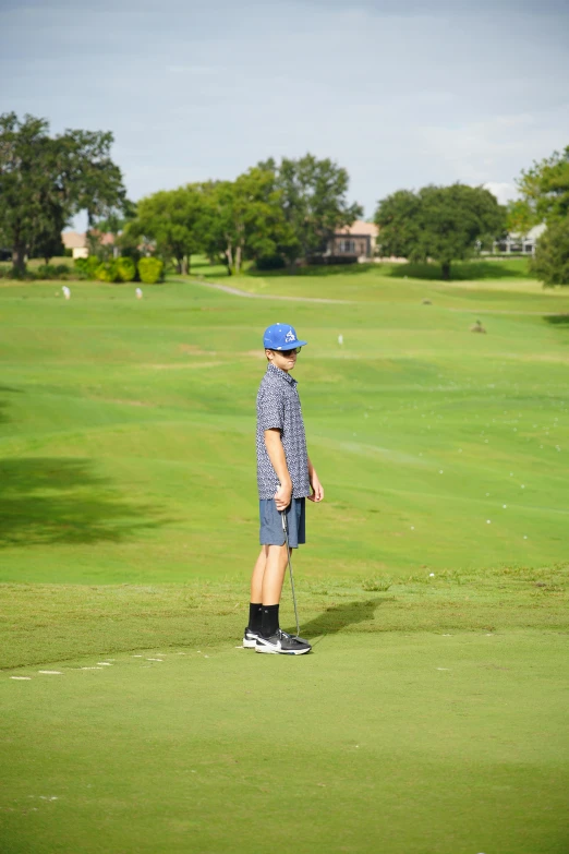 a man on the golf green playing with his back to us