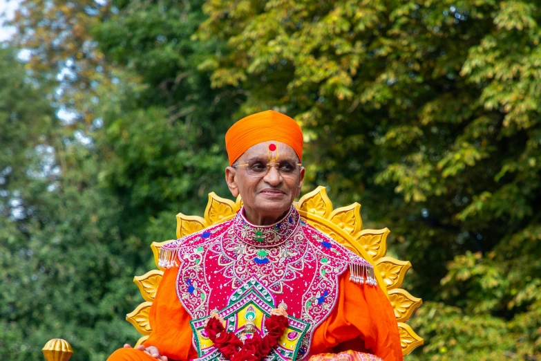 an elderly man sitting on a chair in bright clothes