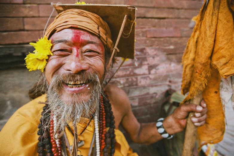 a smiling man with a flower in his hair