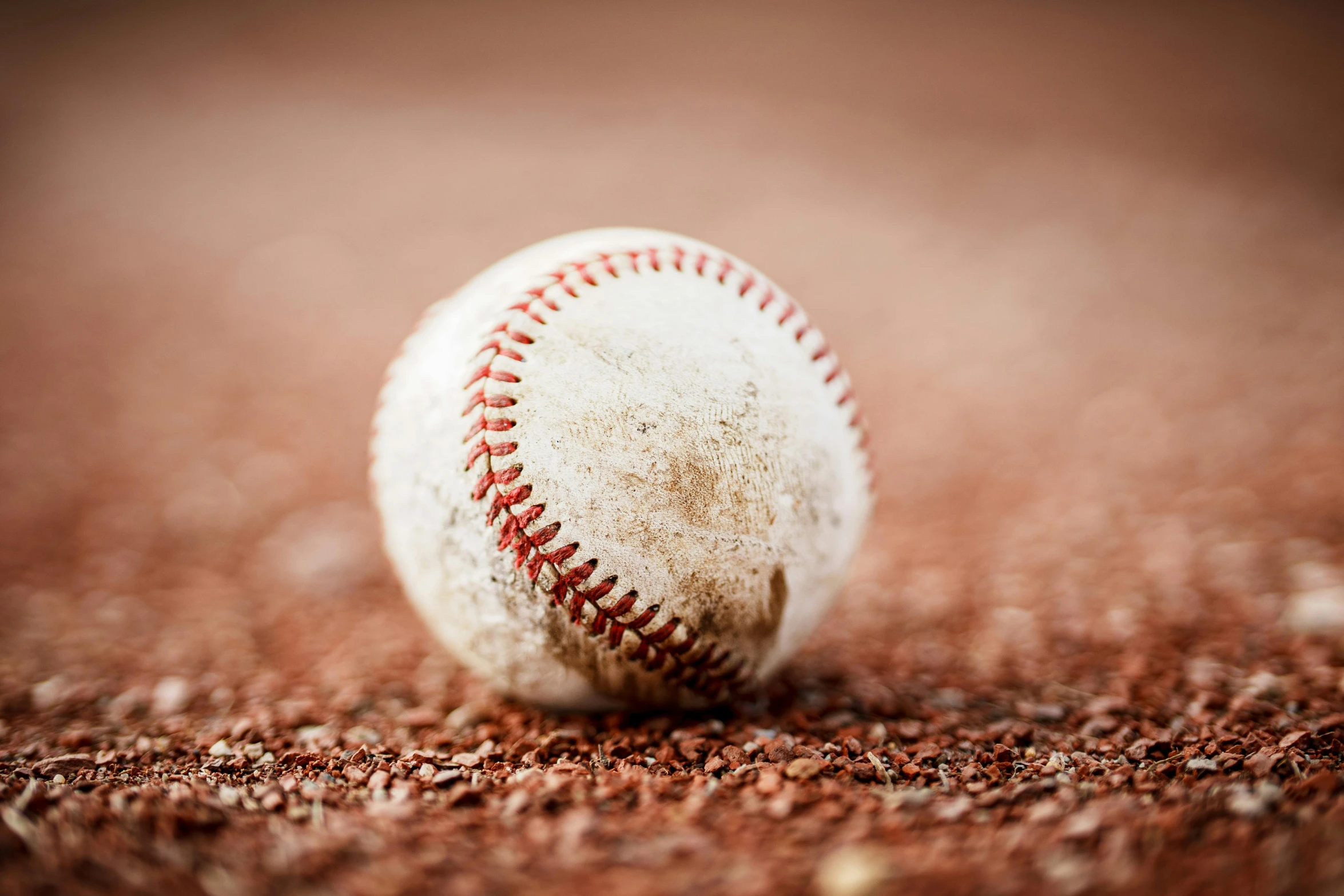 an old baseball on the ground with dirt