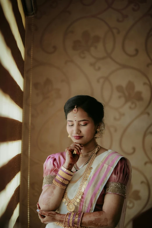 a woman in a pink and white outfit is standing with her hands clasped