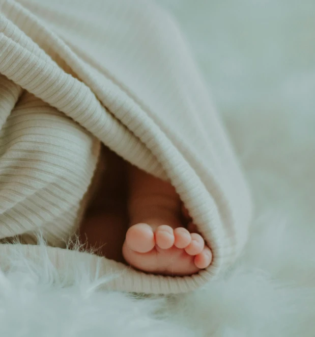 a persons feet under a blanket on a fluffy carpet