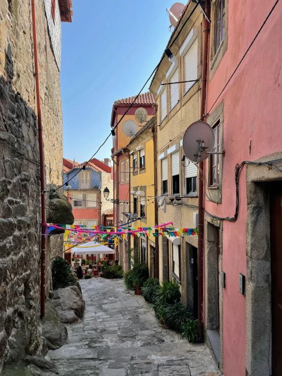 a narrow street of several houses with flags hanging on them