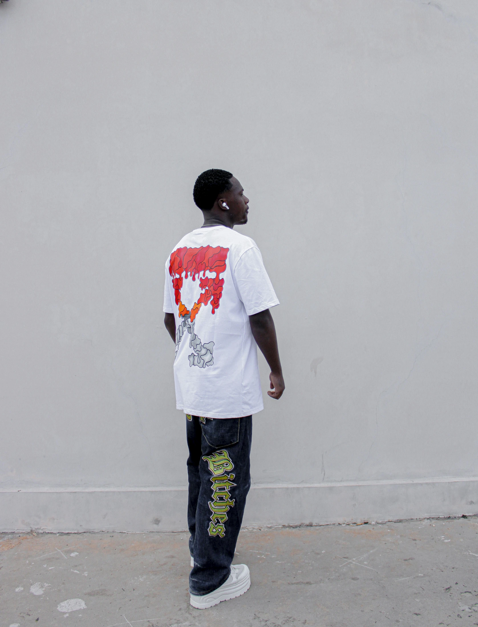 a young man in a white shirt standing with his back to the wall