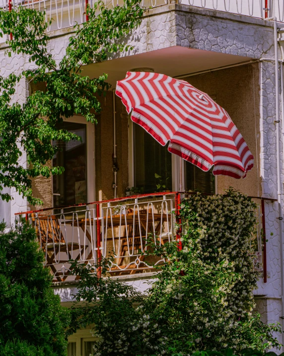 a red and white umbrella on an apartment balcony