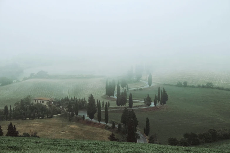 fog covers the green hills and valleys around a small church