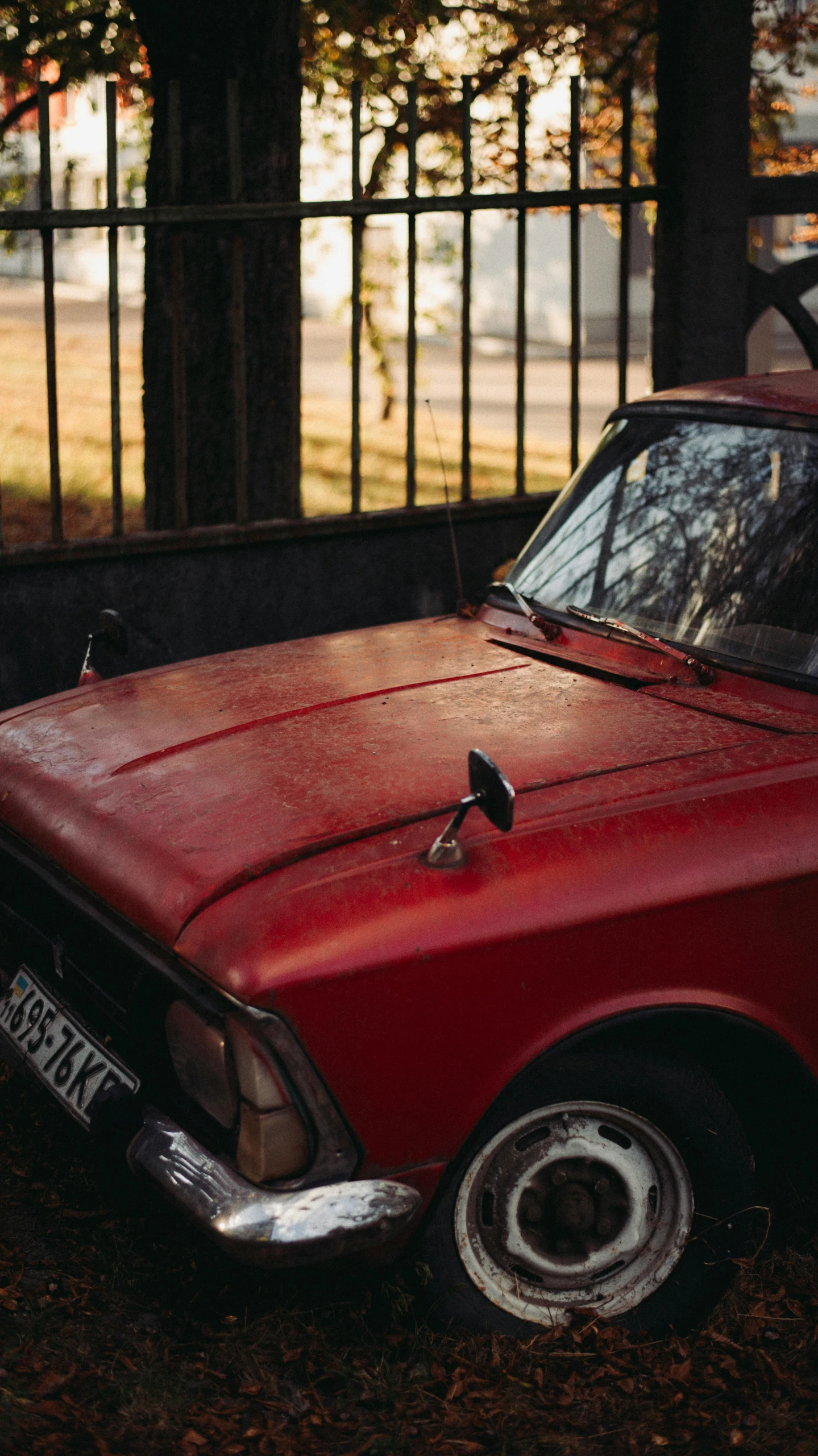 an old red car parked in front of a fence