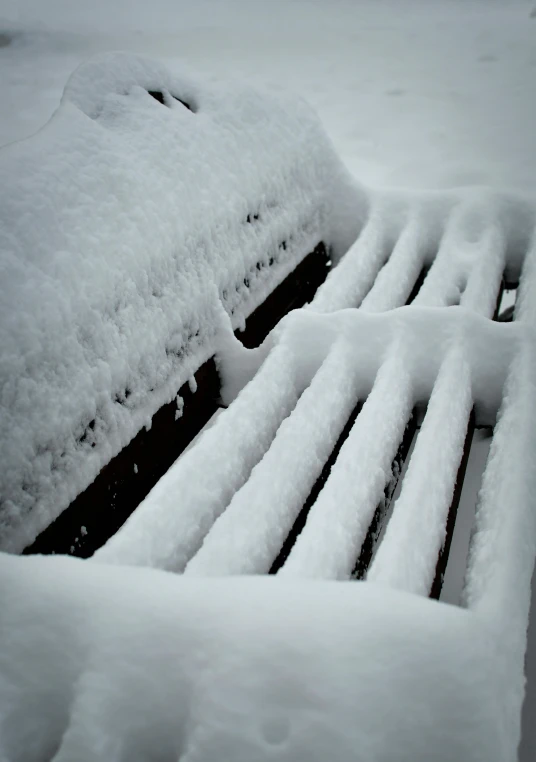 a park bench covered in snow with the seat missing