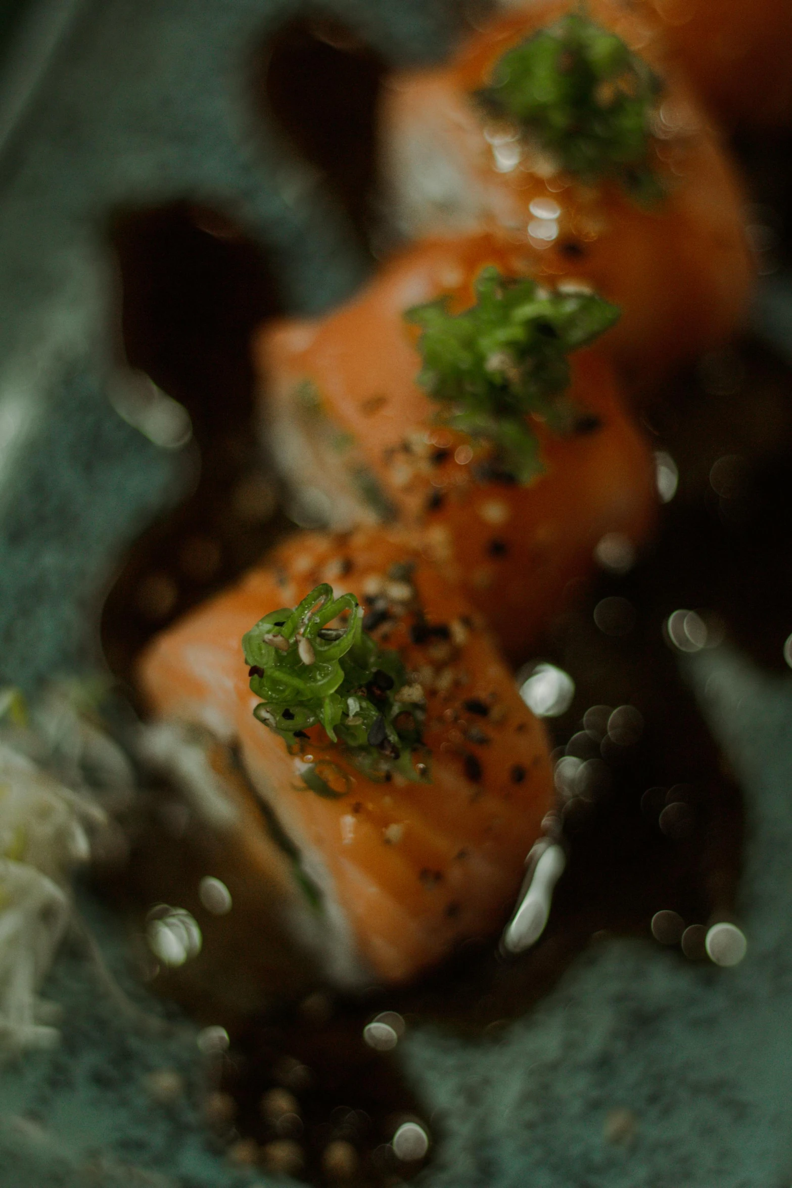 several pieces of salmon on a plate with sauce and sprig of parsley