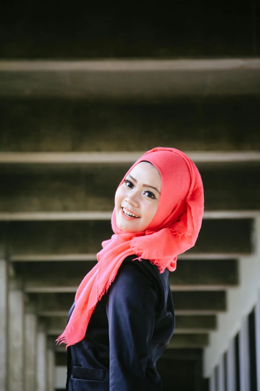 a girl in a hijab is standing under an overpass