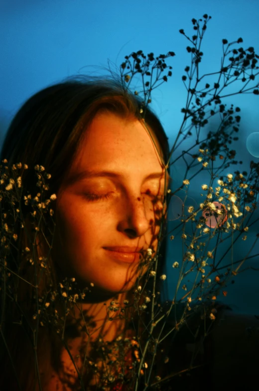 the girl is staring at the flower next to her head