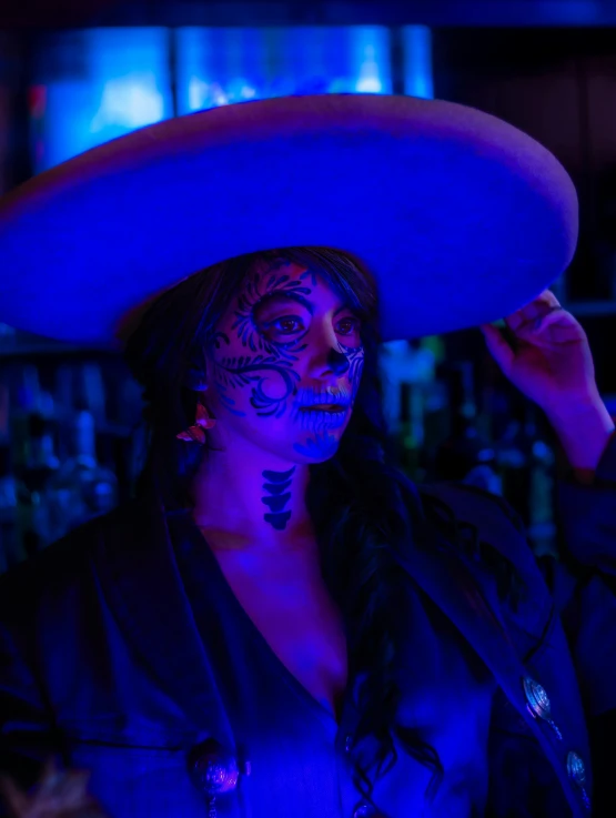 a woman wearing mexican attire standing in front of a neon light
