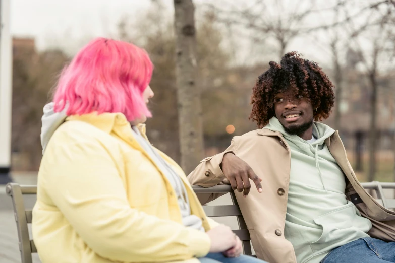 two people sitting on a bench in the park