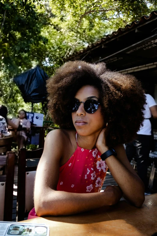 a woman with sunglasses sitting at a table outside