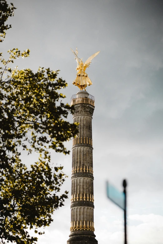 an artistic golden statue atop a tall brick pillar