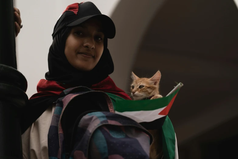 there is a female wearing a black hoodie and holding a cat