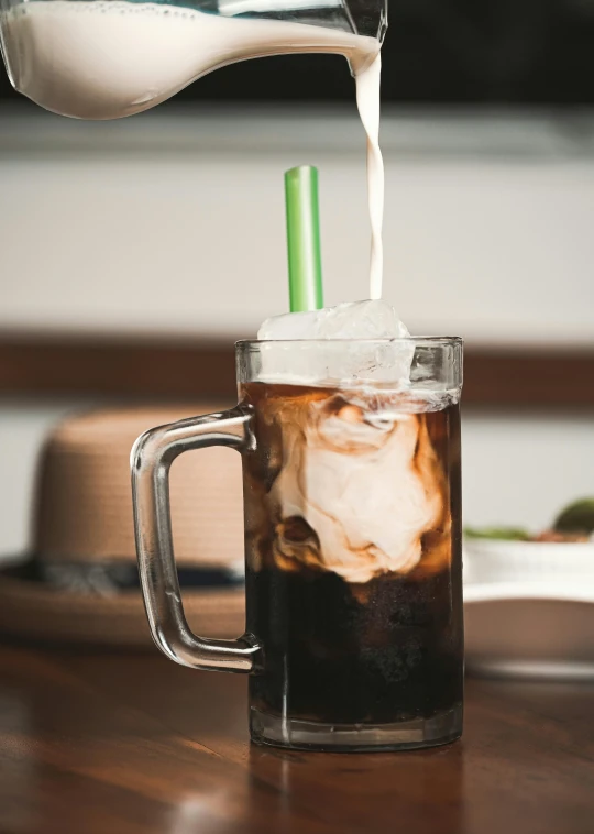 a beverage being poured into a glass mug