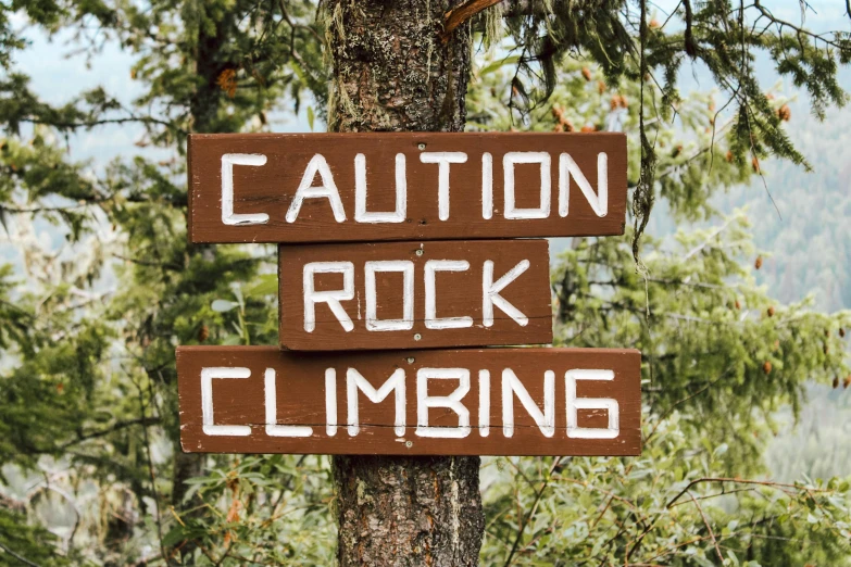 brown caution rock climbing sign with white writing