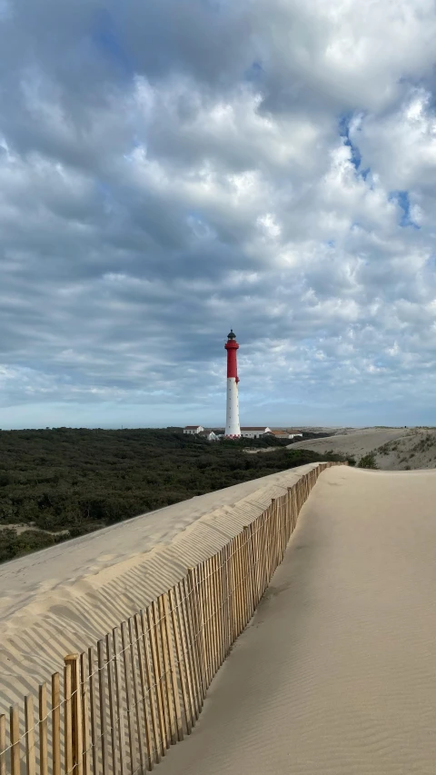 a lighthouse next to a fence at the beach