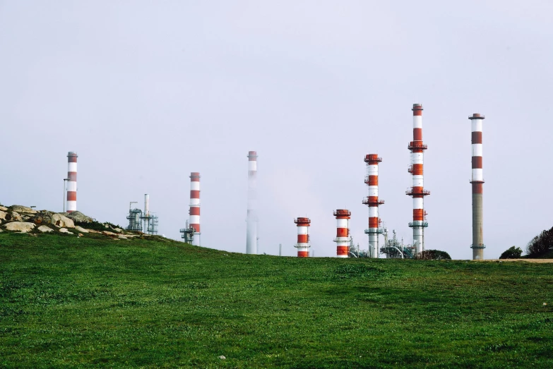 a hillside with red and white chimneys in the sky