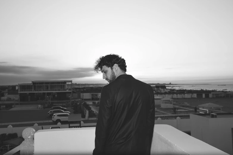 man on rooftop gazing at sunset, with buildings in background