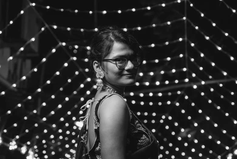 a woman with eye glasses standing in front of christmas lights