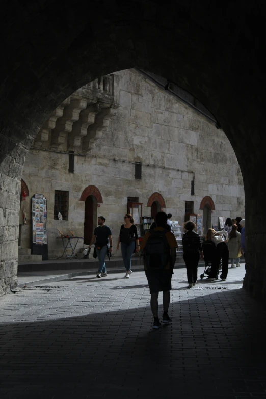 people walk beneath an arched bridge near buildings