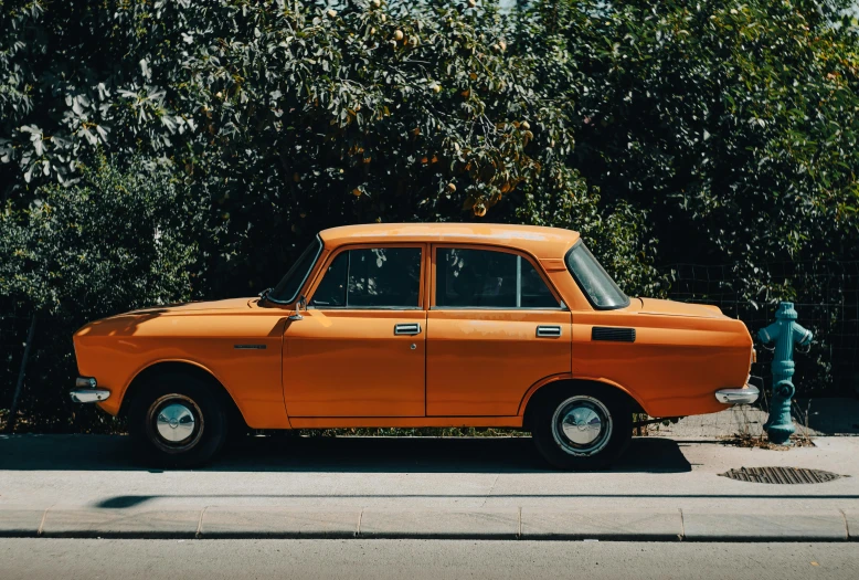 an orange car parked in front of a parking meter