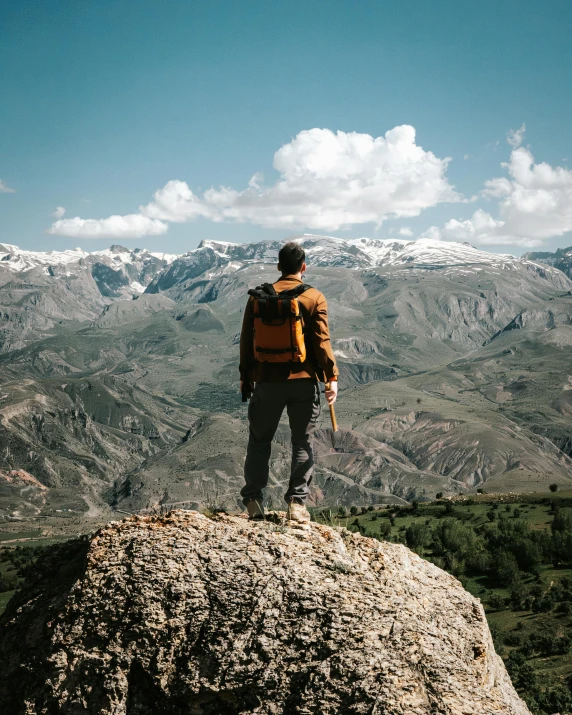 a man with a backpack stands on top of a rock