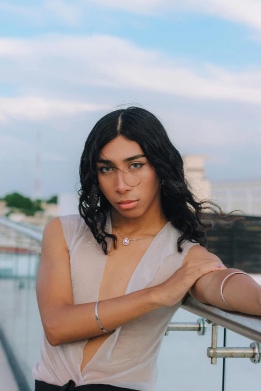 a woman posing on a balcony in a white top