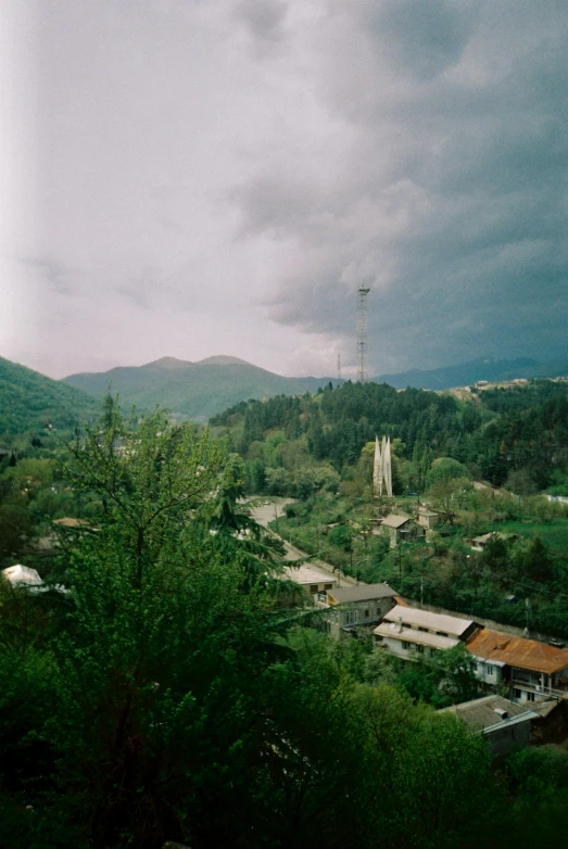 a small town with hills and clouds in the background