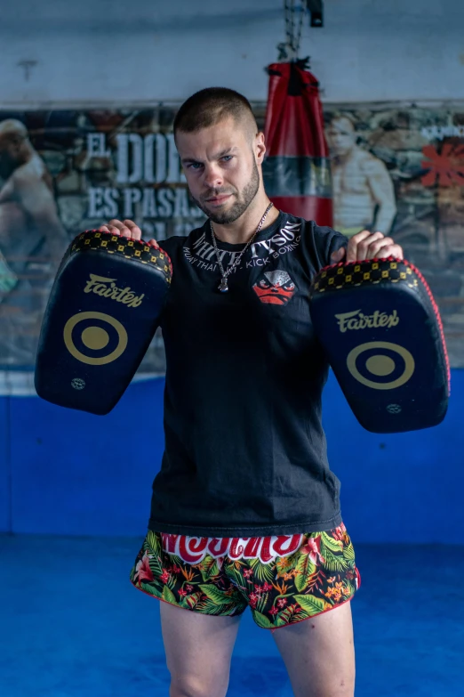 man with one leg up posing with two punching pads