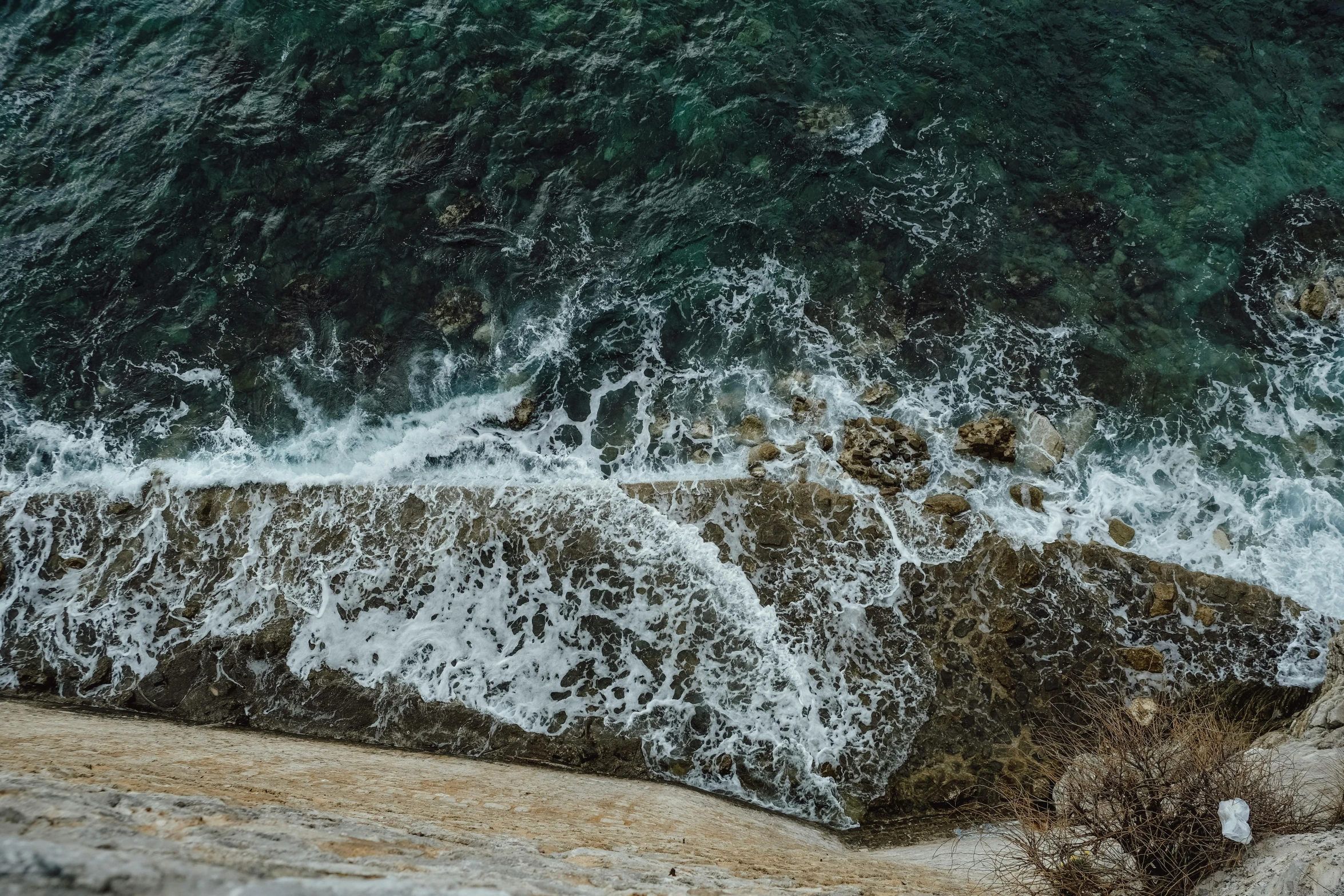 waves are breaking over the rocky shoreline and ocean water