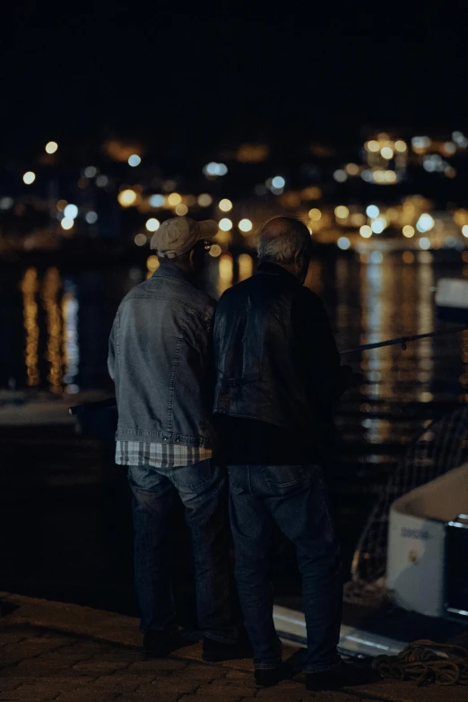 two men standing next to each other near the water
