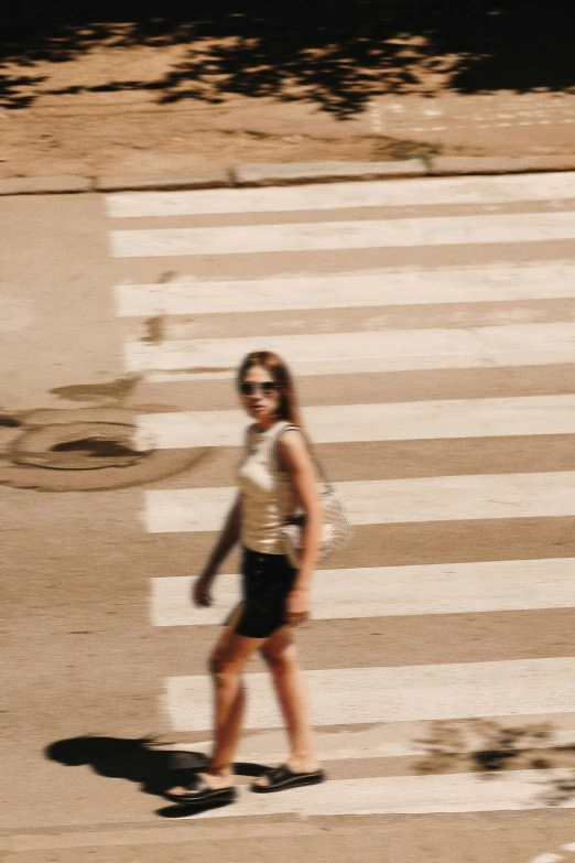 woman walking across a street while wearing sunglasses