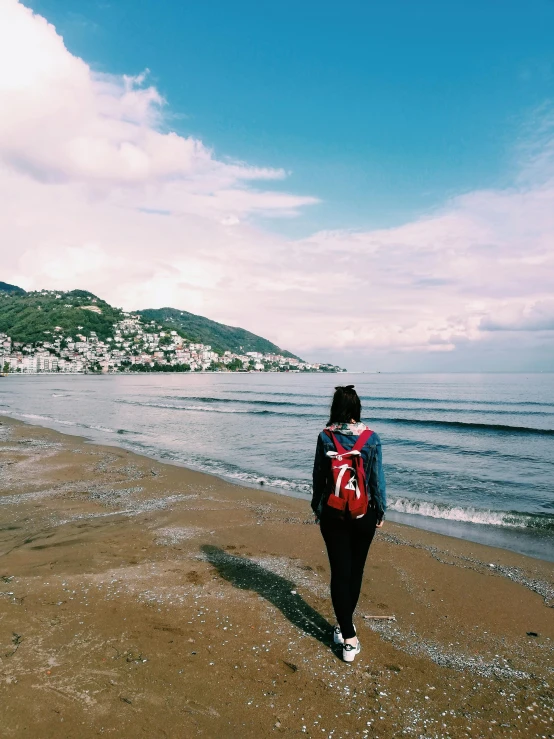 a person walking down a beach with mountains in the background