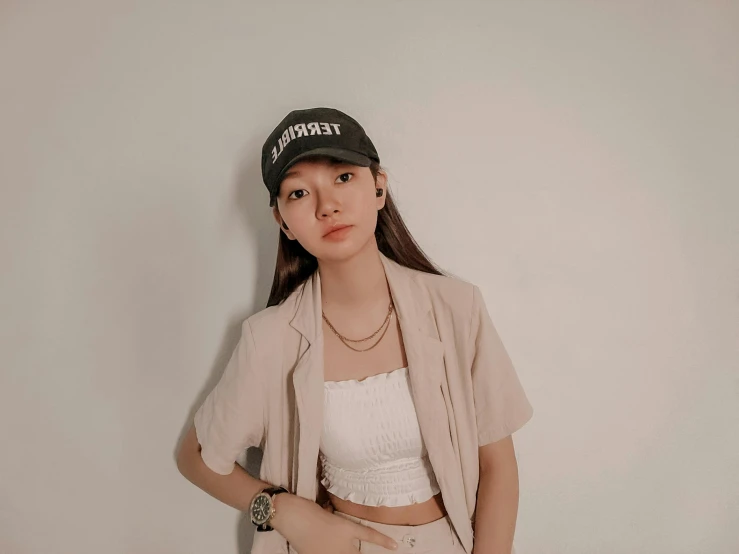 a young woman wearing a baseball cap leaning against a wall