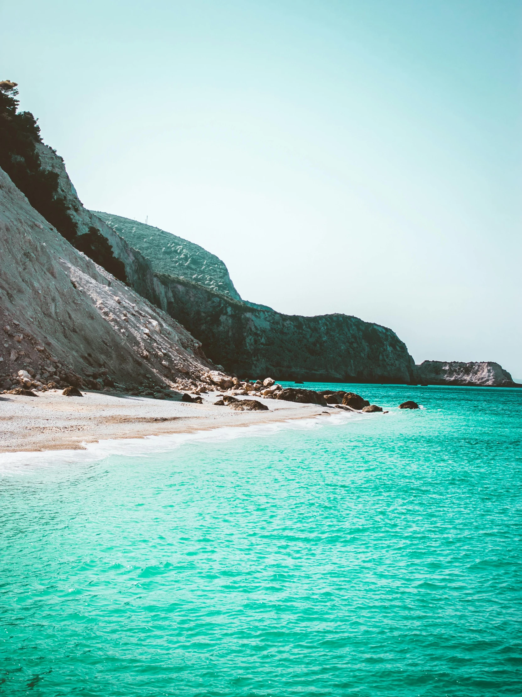 a sandy beach with green and white water