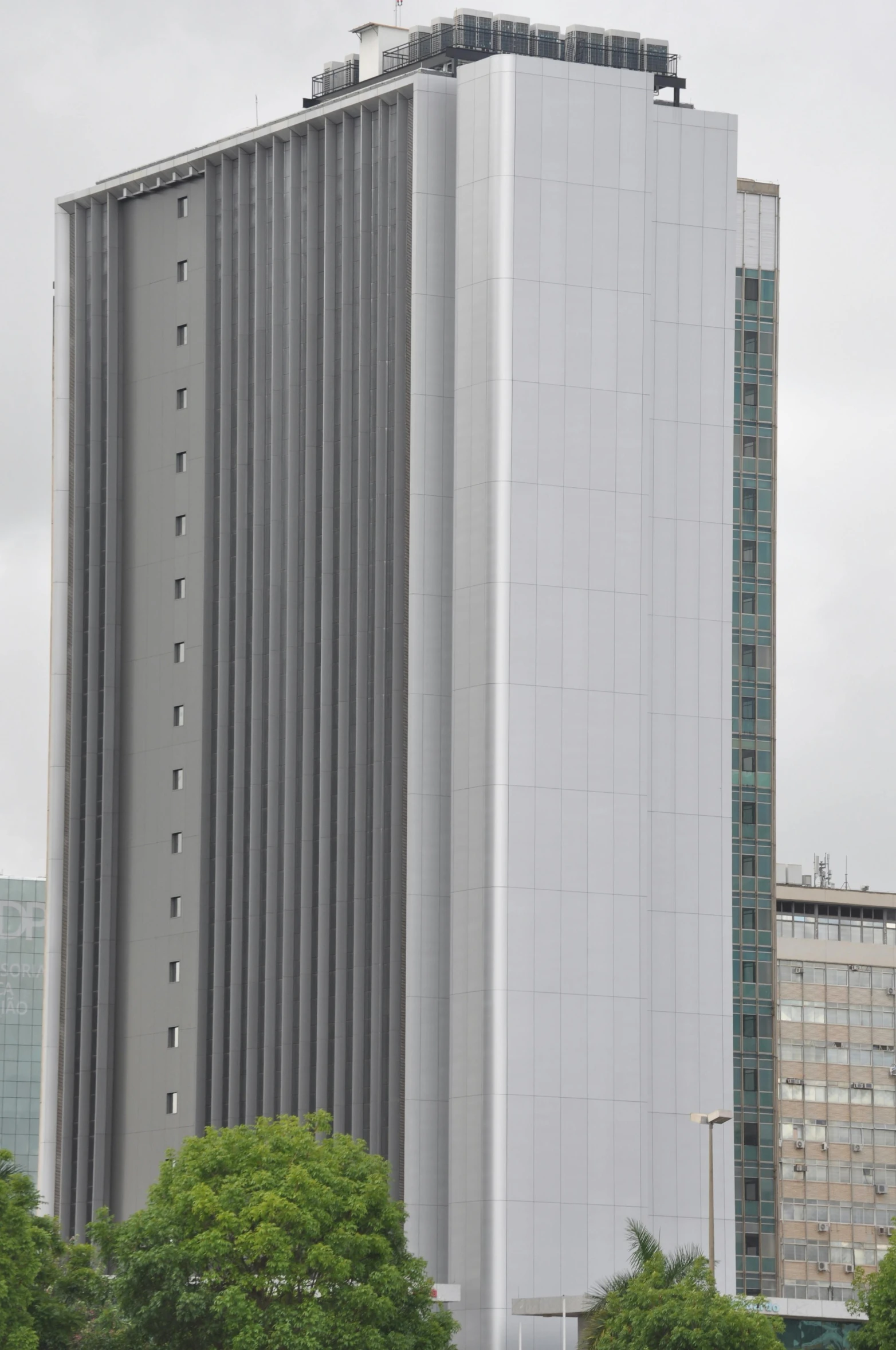 a tall grey building next to trees and buildings