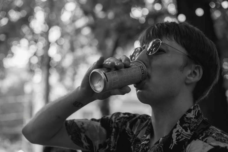 a black and white image of a man drinking from a soda cup