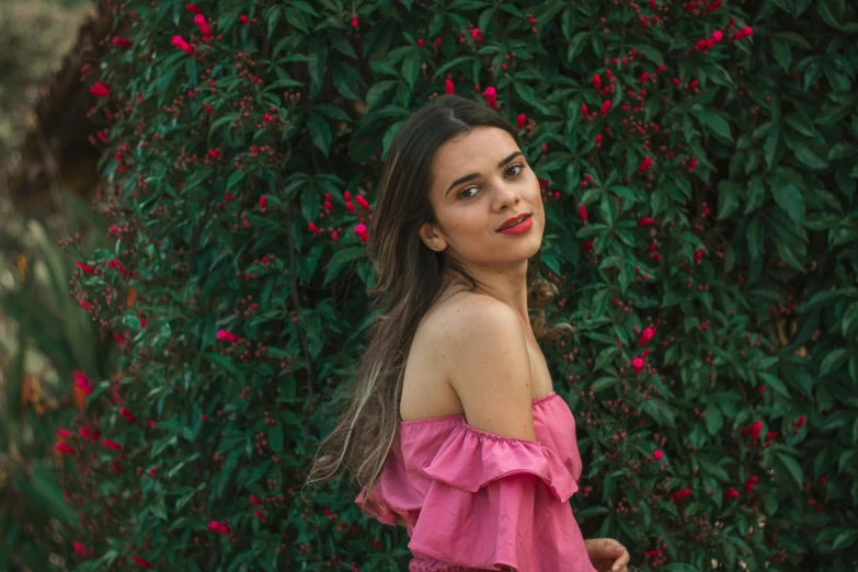 the woman is posing near some bushes with a frizz of flowers